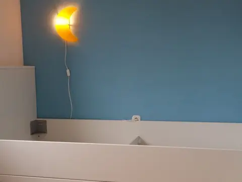 Krevet s ladicama uz plavi zid
